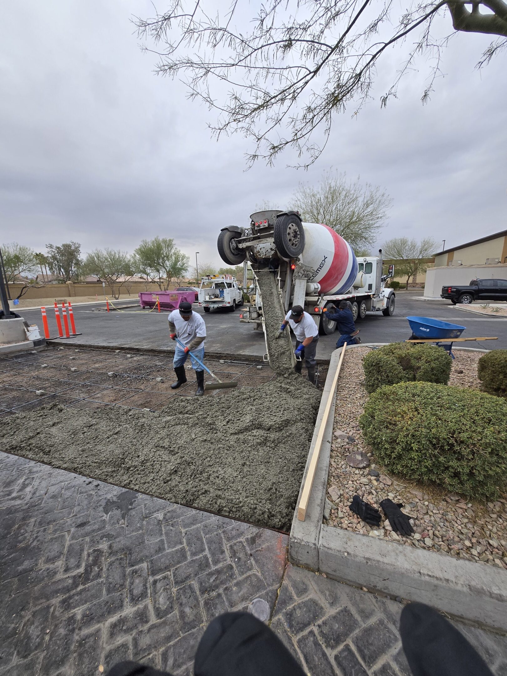 Workers pour concrete from a mixer truck at a construction site.