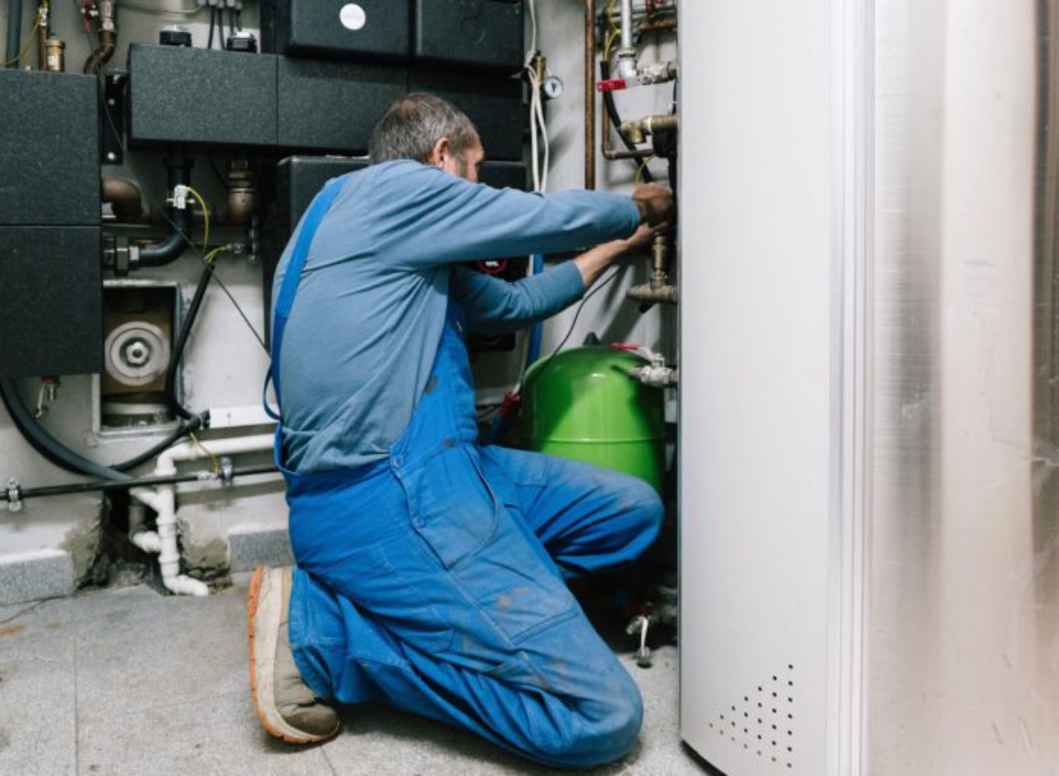 Technician in blue overalls repairing a boiler.